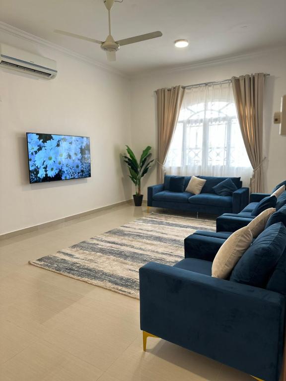 ein Wohnzimmer mit zwei blauen Sofas und einem Teppich in der Unterkunft Homely.8 شقة in Firq