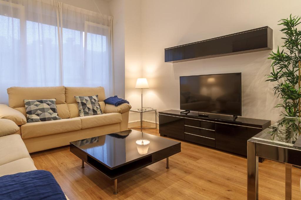 een woonkamer met een bank en een flatscreen-tv bij Konporte Apartamento Renovado con Wifi y Garaje in Getxo