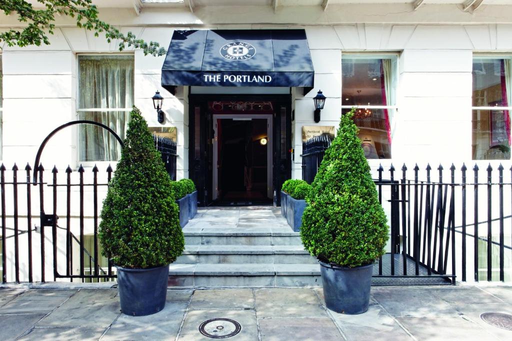 eine Eingangstür eines Gebäudes mit zwei Topfbäumen davor in der Unterkunft Grange Portland Hotel in London