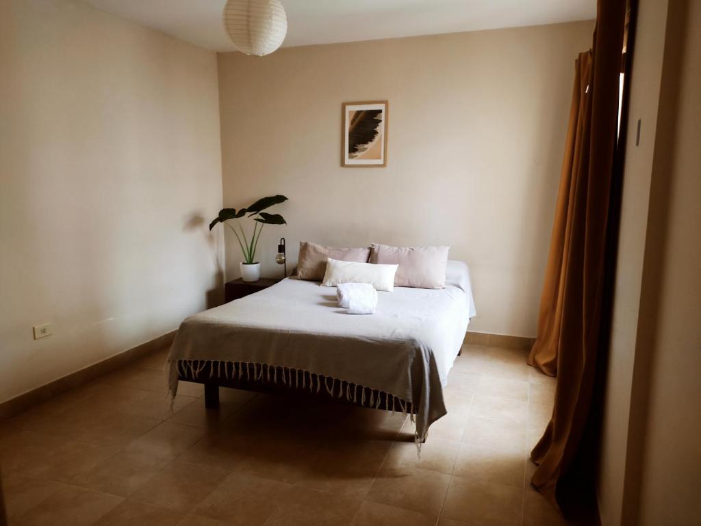 1 dormitorio con 1 cama con sábanas y almohadas blancas en Boho 270 Familiar en San Salvador de Jujuy