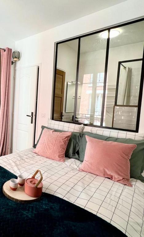 - un lit avec des oreillers roses et un plateau dans l'établissement Joli Appartement à 15min des Champs Elysée, à Saint-Ouen
