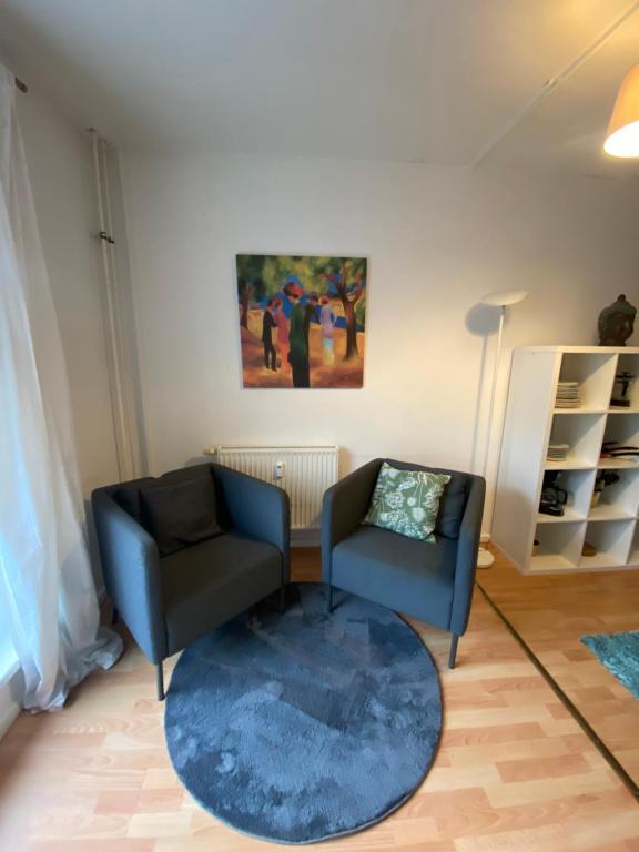 柏林的住宿－Osthafen IV，客厅配有两把椅子和蓝色地毯。