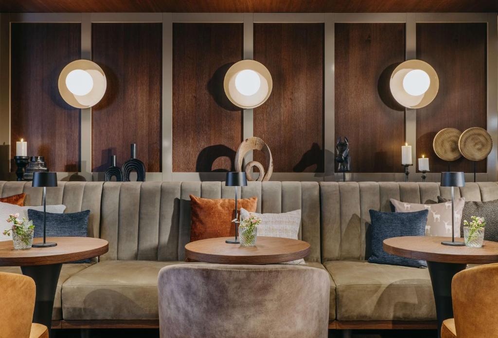a restaurant with a couch and tables and mirrors at Grand Tirolia Kitzbühel - Member of Hommage Luxury Hotels Collection in Kitzbühel