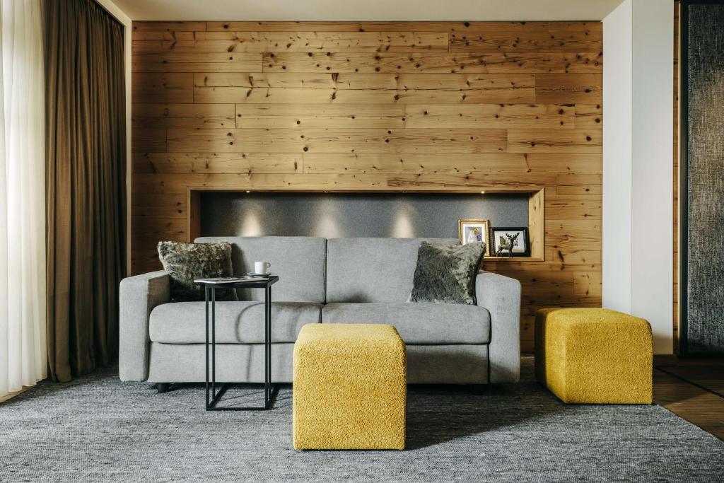 a living room with a couch and two yellow stools at Grand Tirolia Kitzbühel - Member of Hommage Luxury Hotels Collection in Kitzbühel