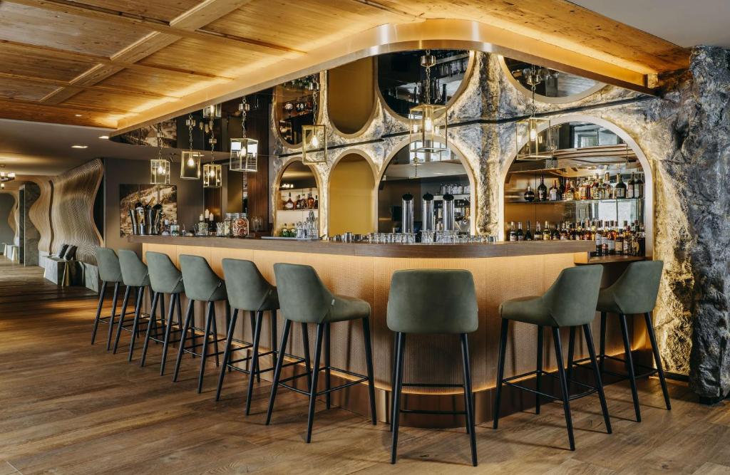 a bar with green stools in a room with a stone wall at Grand Tirolia Kitzbühel - Member of Hommage Luxury Hotels Collection in Kitzbühel