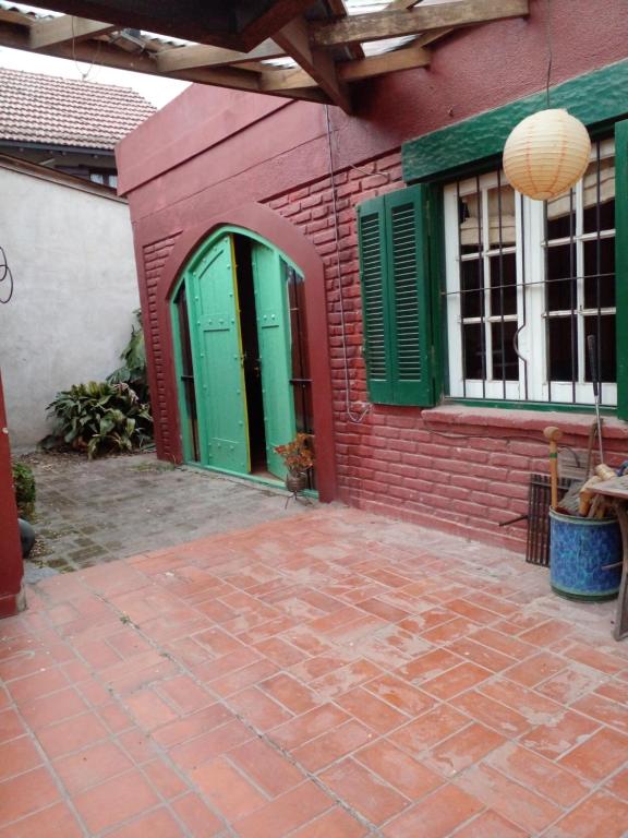 a red brick building with green doors and a patio at Dormi en Mar del Plata! in Mar del Plata