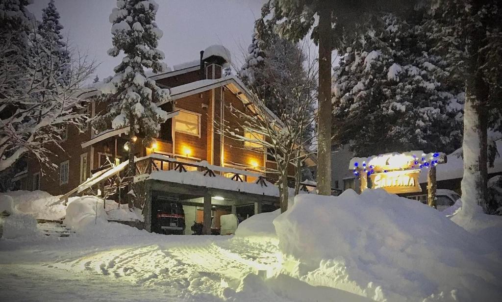 una casa cubierta de nieve por la noche en B&B Santana Hakuba, en Hakuba