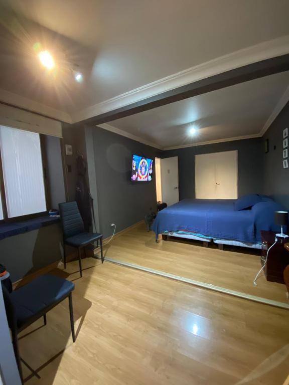 um quarto com uma cama azul e uma televisão em ambry em Calama