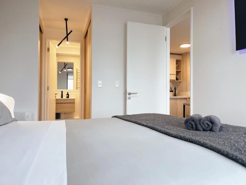 um quarto com uma cama branca com duas toalhas em Departamento Centro moderno con balcón em Temuco
