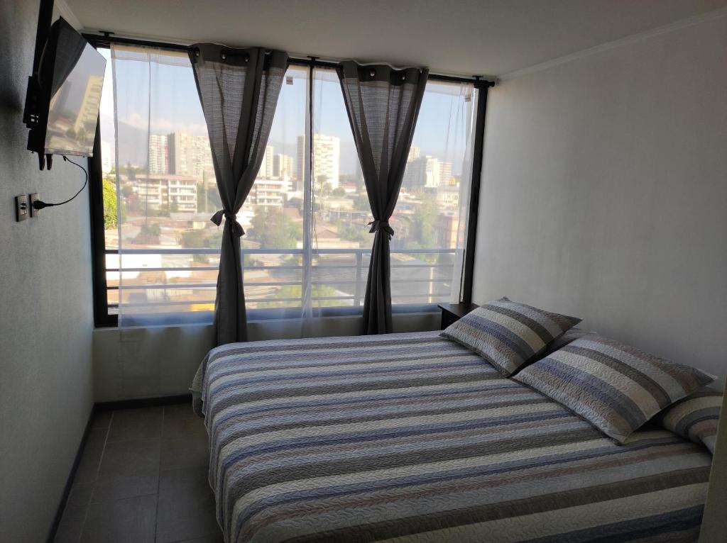 een slaapkamer met een bed en een groot raam bij Departamento arriendo diario in Santiago