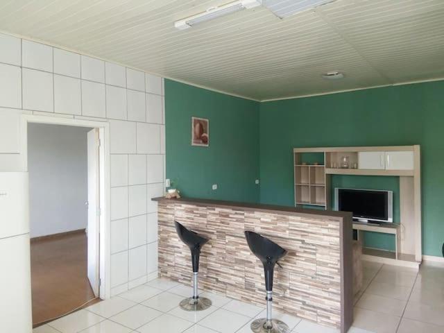 庫里奇巴的住宿－Hospedagem com carinho!，一间设有两张黑色椅子的房间,房间拥有绿色的墙壁