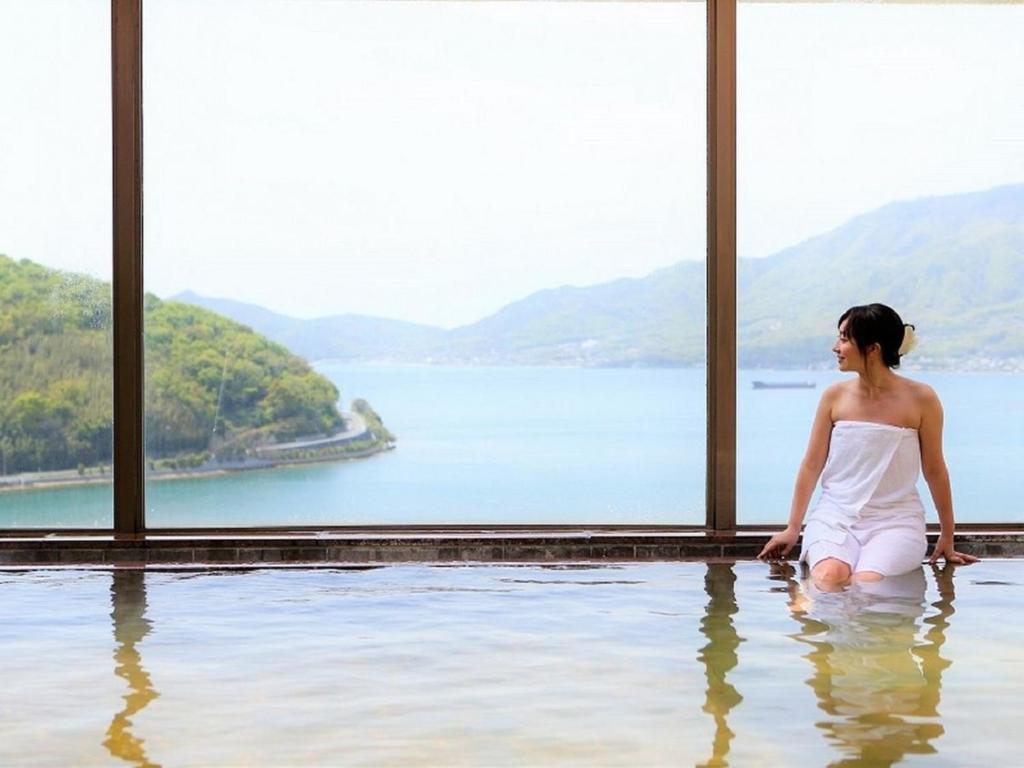 una mujer sentada en el agua en una piscina en Bay Resort Hotel Shodoshima en Shodoshima