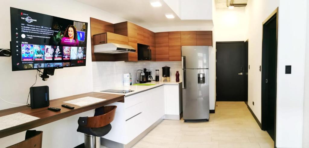 Il comprend une cuisine équipée d'un réfrigérateur et une télévision murale. dans l'établissement Tijax 10 apartamento en zona 10, à Guatemala
