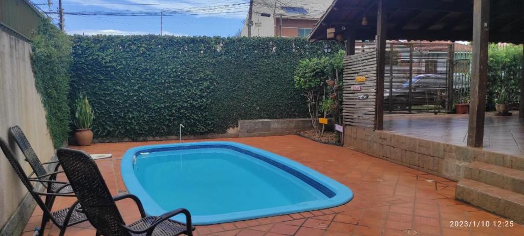 a swimming pool in a yard with chairs and a fence at Casa Da Tiete - Foz do Iguaçu - PR in Foz do Iguaçu