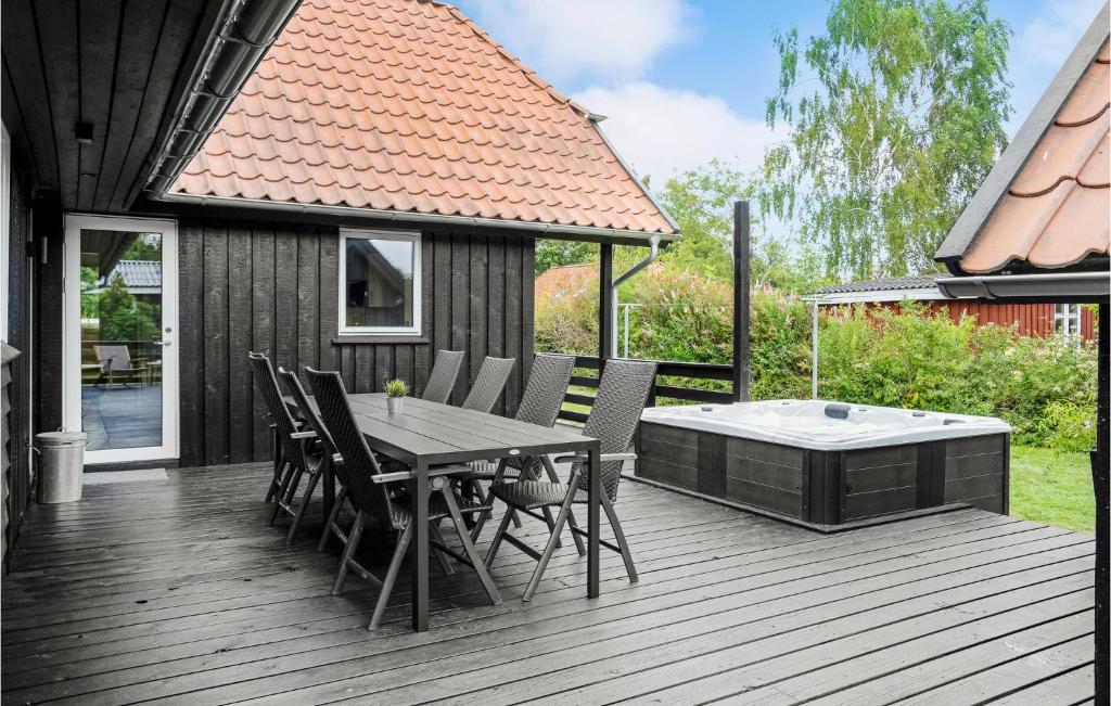 a wooden deck with a table and chairs and a hot tub at Beautiful Home In Juelsminde With Sauna, Wifi And Private Swimming Pool in Sønderby