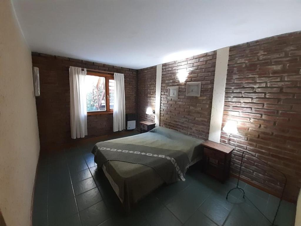 1 dormitorio con cama y pared de ladrillo en Cabaña Bustillo en San Carlos de Bariloche