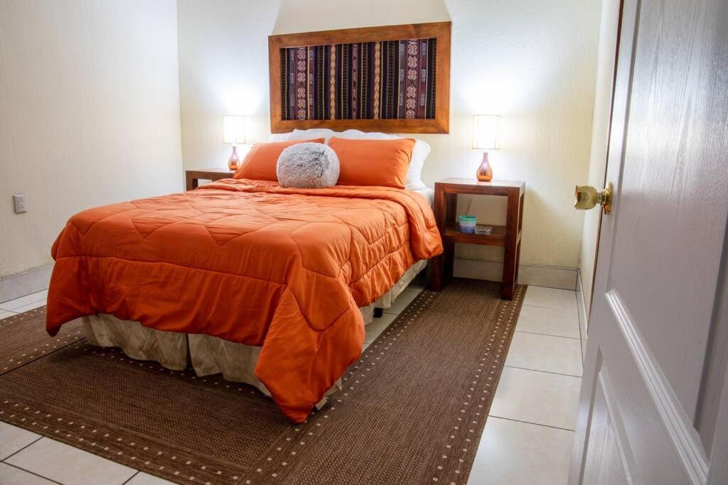 a bedroom with a bed with an orange blanket at COZY Fully equipped private apartment in Chimaltenango
