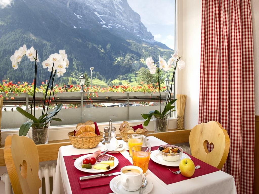 uma mesa com comida para o pequeno almoço e vista para uma montanha em Hotel Bernerhof Grindelwald em Grindelwald
