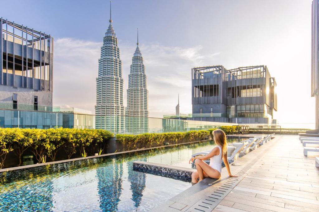 a woman sitting on the edge of a swimming pool with the city at Star Suites KLCC in Kuala Lumpur