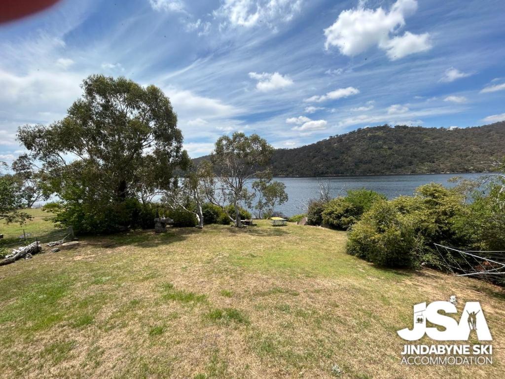 a large grass field next to a body of water at Banksia 1 in Jindabyne