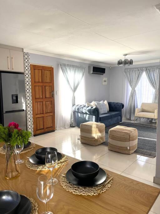 ein Wohnzimmer mit einem Tisch und einem blauen Sofa in der Unterkunft Are you travelling to Pretoria? in Pretoria