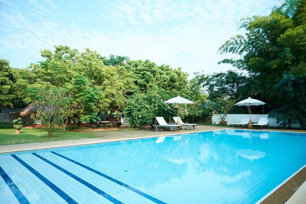 een groot blauw zwembad met 2 stoelen en parasols bij resort hoshihana in Chiang Mai