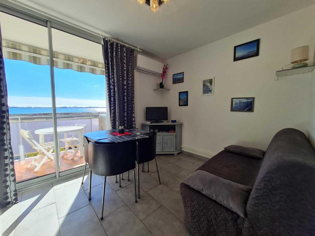 d'un salon avec un canapé et une table ainsi que d'un balcon. dans l'établissement Appartement climatisé, proche thermes, garage privé, Wi-Fi - Balaruc-les-Bains - FR-1-503-160, à Balaruc-les-Bains