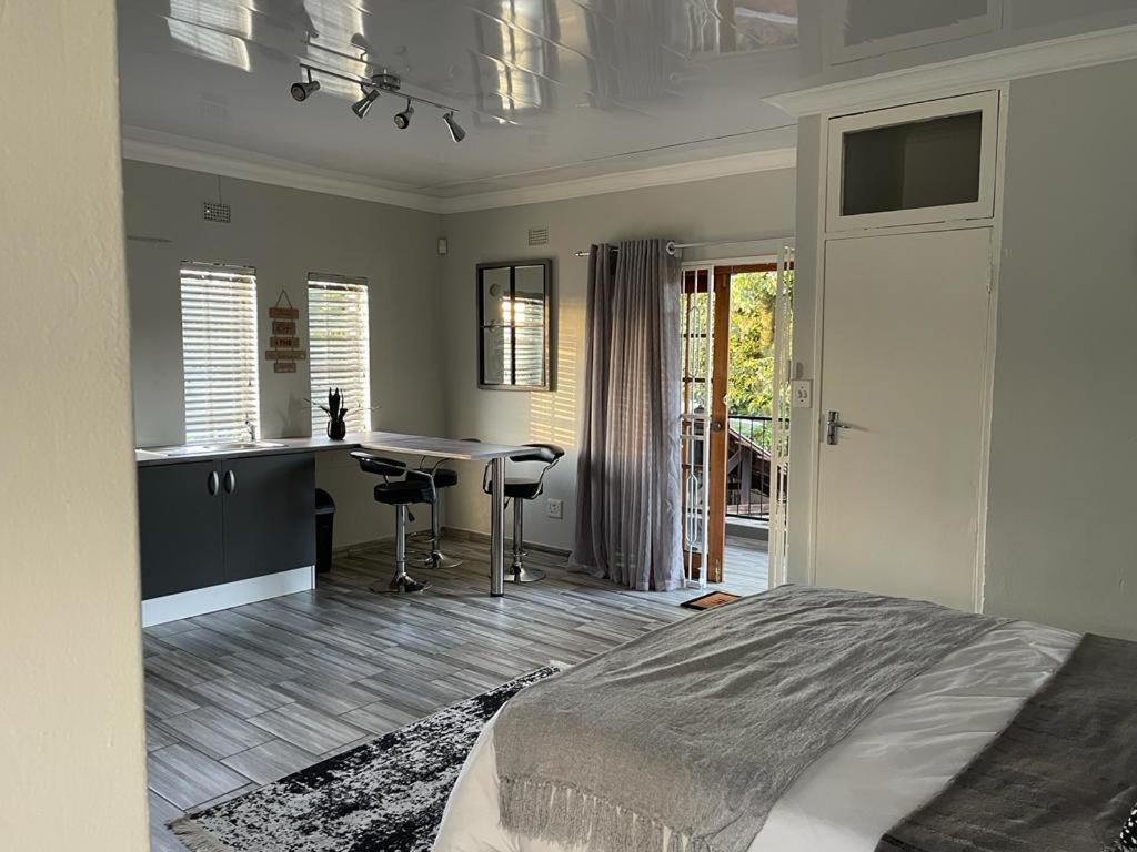 a bedroom with a bed and a desk and a kitchen at 22 on Mirabel in Kempton Park