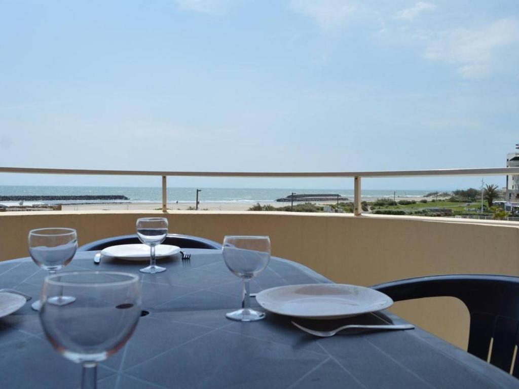 - une table avec des verres à vin et une vue sur la plage dans l'établissement Cap d'Agde : T2 avec piscine, parking, à 50m de la plage - FR-1-249-71, au Cap d'Agde