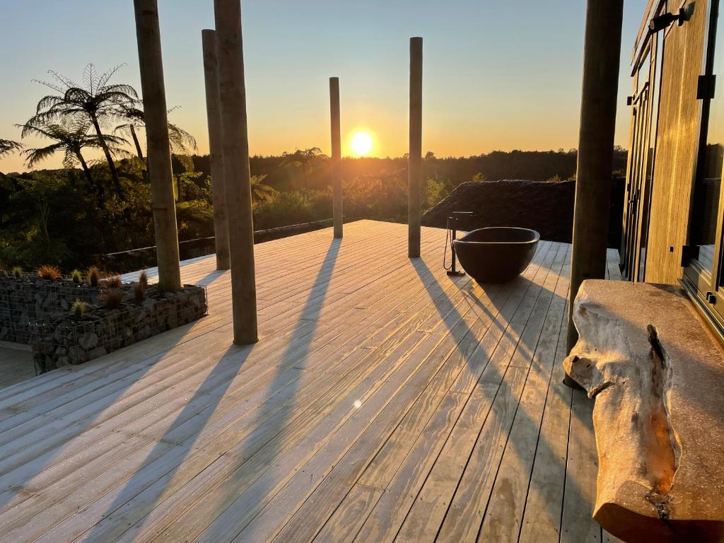 a wooden deck with the sunset in the background at Pukeko Lane in Tauranga