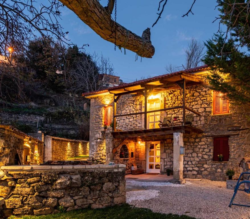 a stone house with lights on it at night at Βίλα Αρμονία Ορεινή Κορινθία in Krionérion