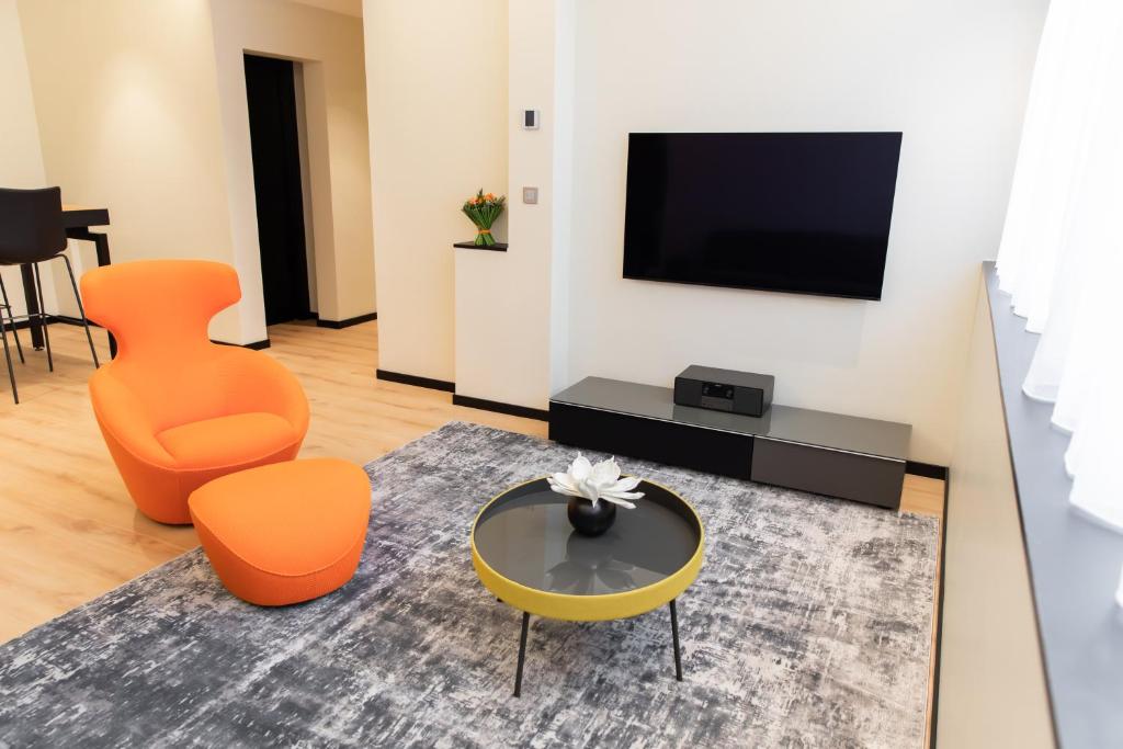 - un salon avec des chaises orange et une télévision dans l'établissement Suite Montrachet 4 personnes vue cathédrale 1 Place de parking, à Dijon