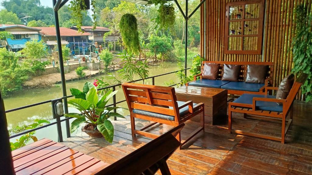 a balcony with chairs and a table and a view of a river at Baan Canalee (บ้านคานาลี) in Phra Nakhon Si Ayutthaya