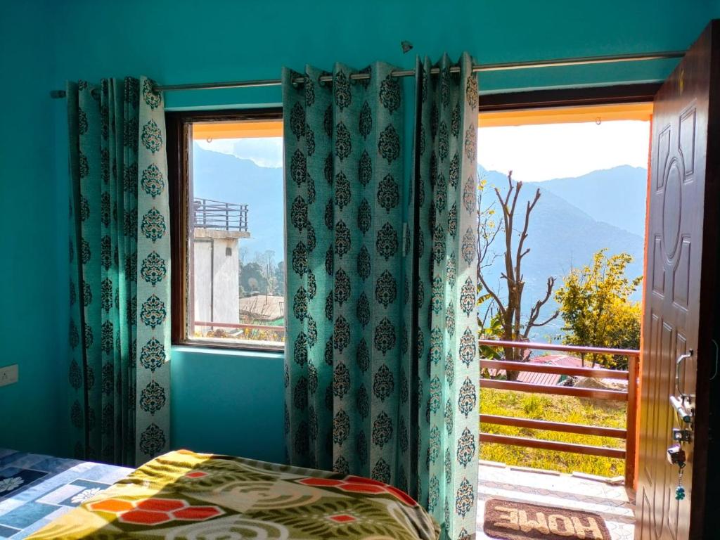 a bedroom with a window with a view of a mountain at Pandava's Cafe & Stay in Chopta