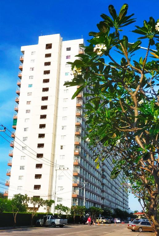 a tall white building with cars parked in front of it at Jomtien beach Condominium S2 in Jomtien Beach