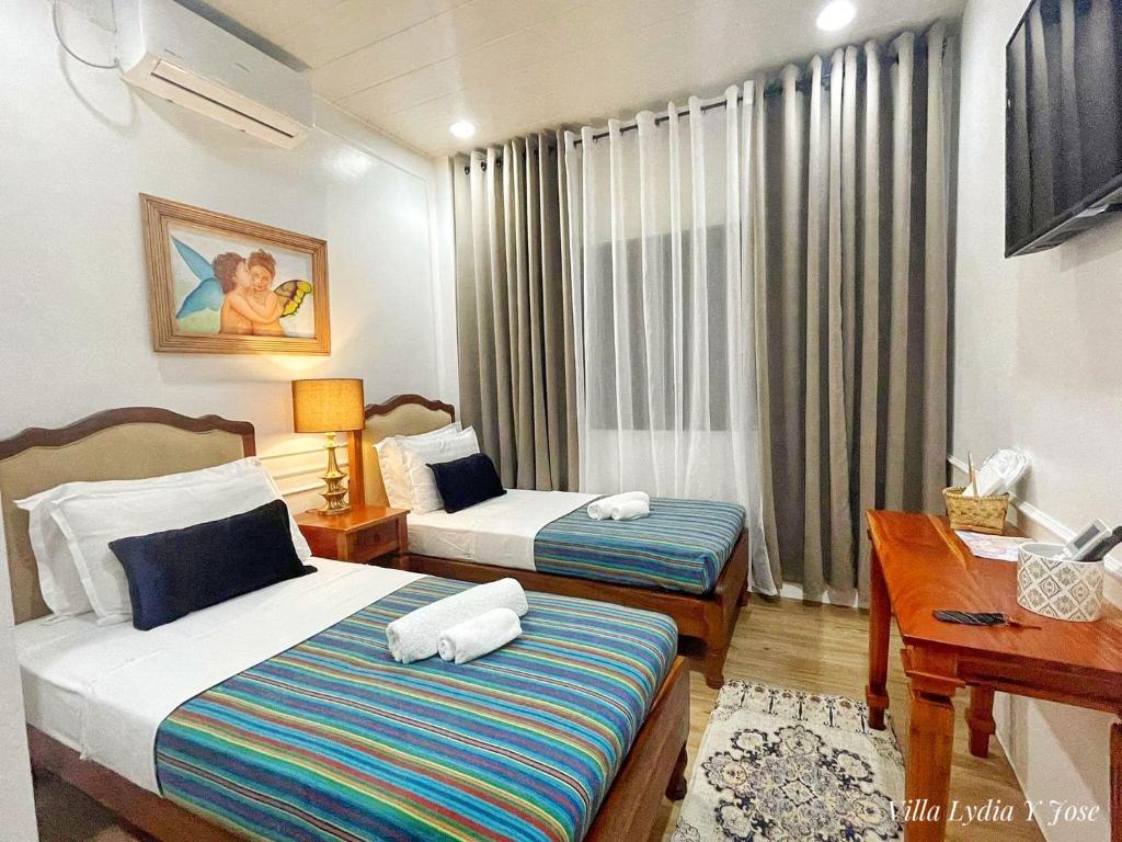 a hotel room with two beds and a desk at Villa Lydia y Jose Heritage Hotel in Bayubay Sur