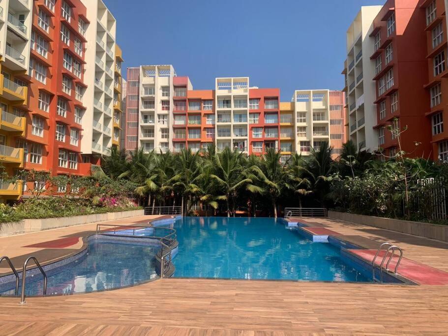 a swimming pool in front of some apartment buildings at Studio Apartment Near Airport 306 in Dabolim