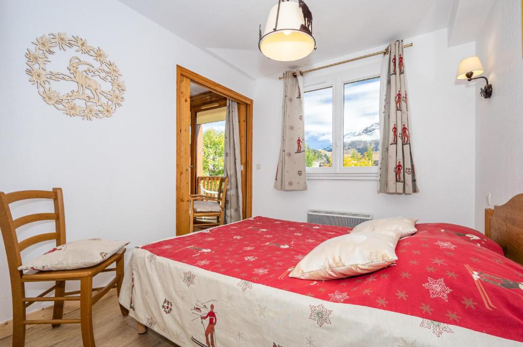 a bedroom with a red bed with a chair and a window at A105- Appartement 2 pieces cabine 6 personnes in Orcières