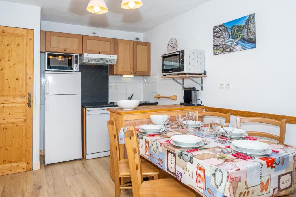 a kitchen with a table with chairs and a tablecloth on it at A105- Appartement 2 pieces cabine 6 personnes in Orcières
