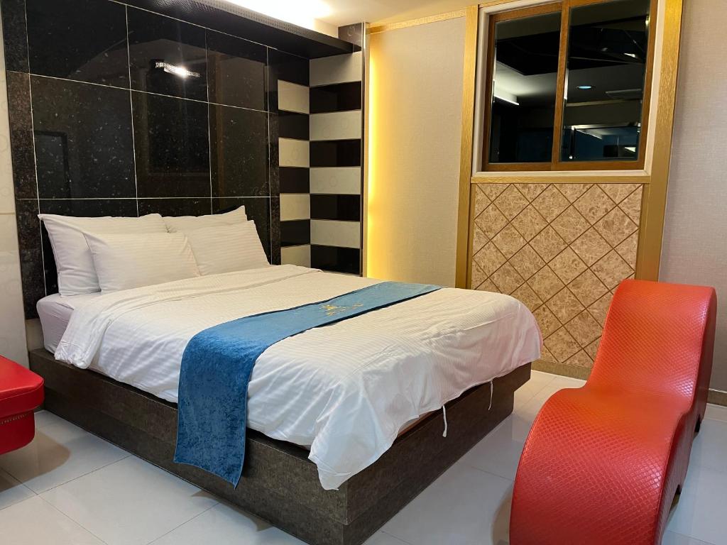 a bedroom with a bed and a red chair at Queen Drive-In Motel in Jeju