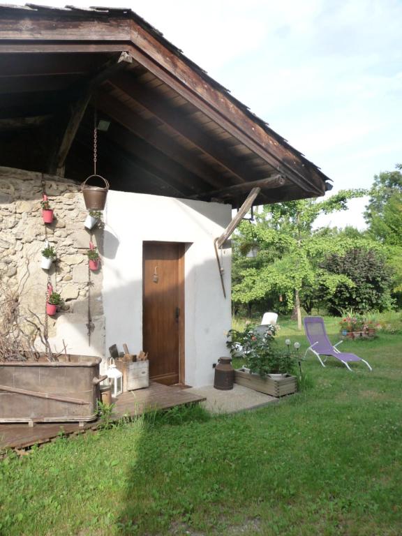 Cabaña blanca con puerta de madera y silla en Rendez-vous au jardin, en Notre Dame-de-lʼOsier