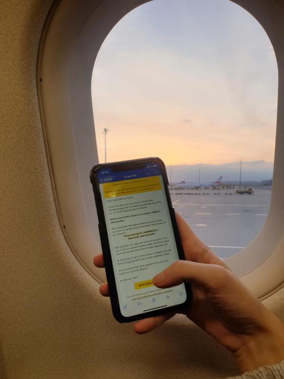 a person holding a cell phone in front of an airplane window at BeFree Hostel - Self-Service in Vienna