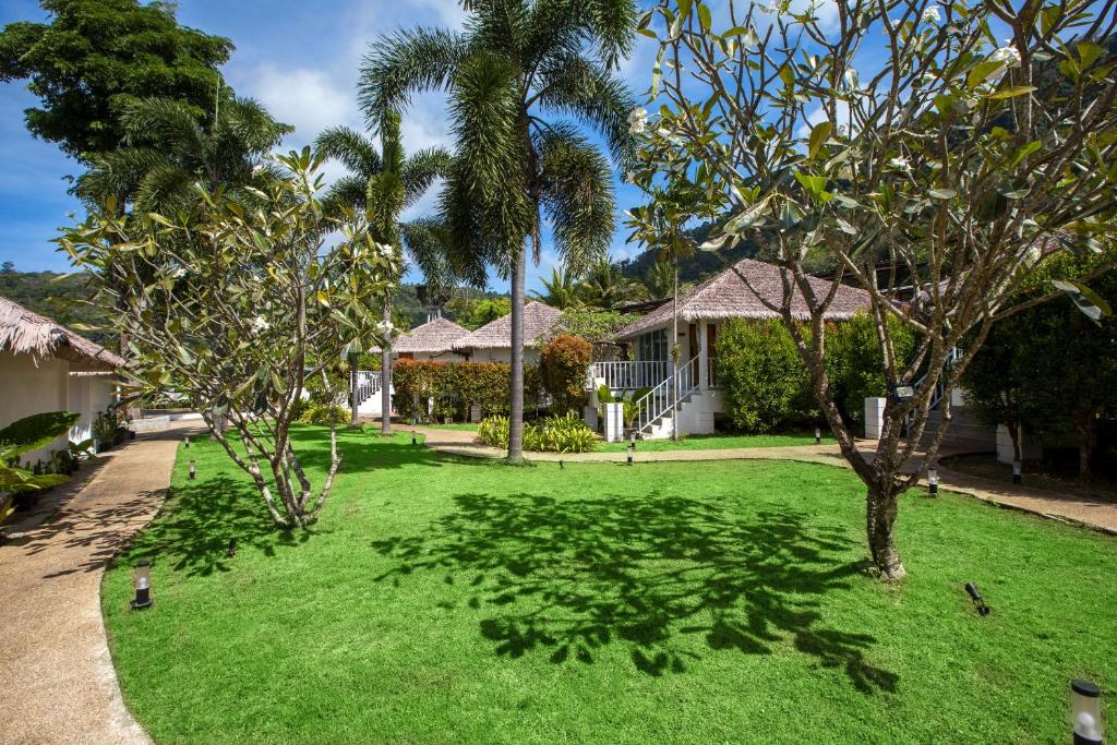 une cour verdoyante avec des palmiers et une maison dans l'établissement Daydream villa resort, à Patong Beach