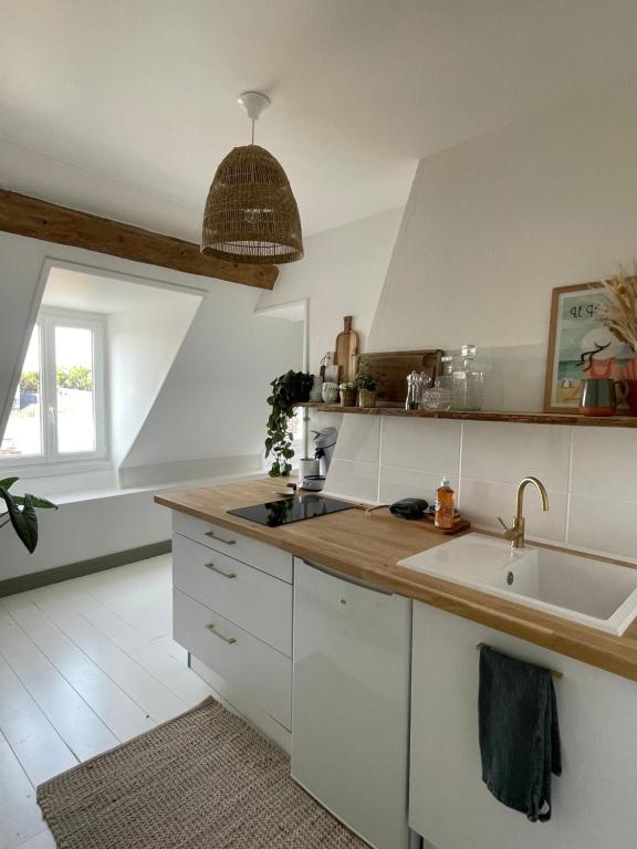 uma cozinha com armários brancos, um lavatório e uma janela em Appartement cosy et lumineux au cœur de Montreuil em Montreuil-sur-Mer