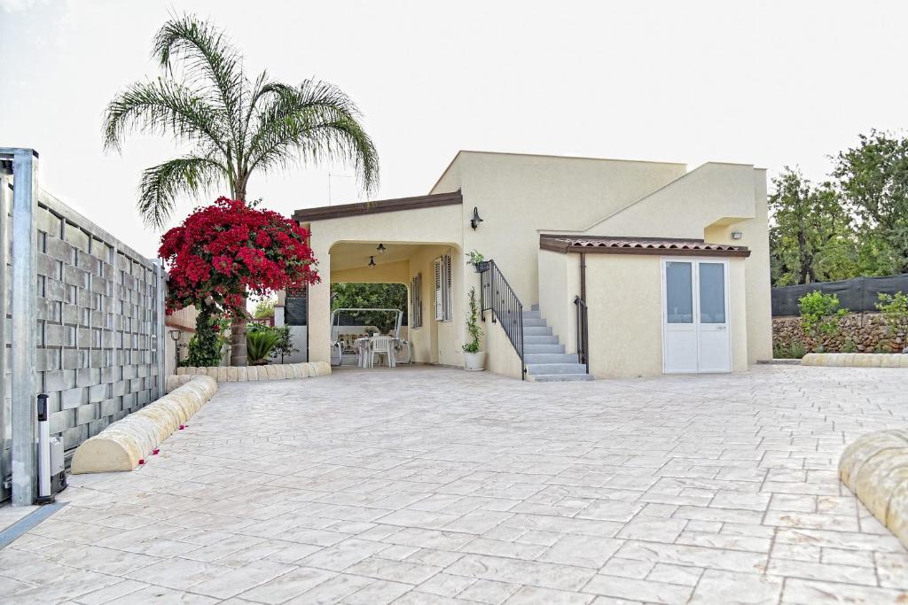 a house with a driveway and a palm tree at La Gardenia in Noto Marina