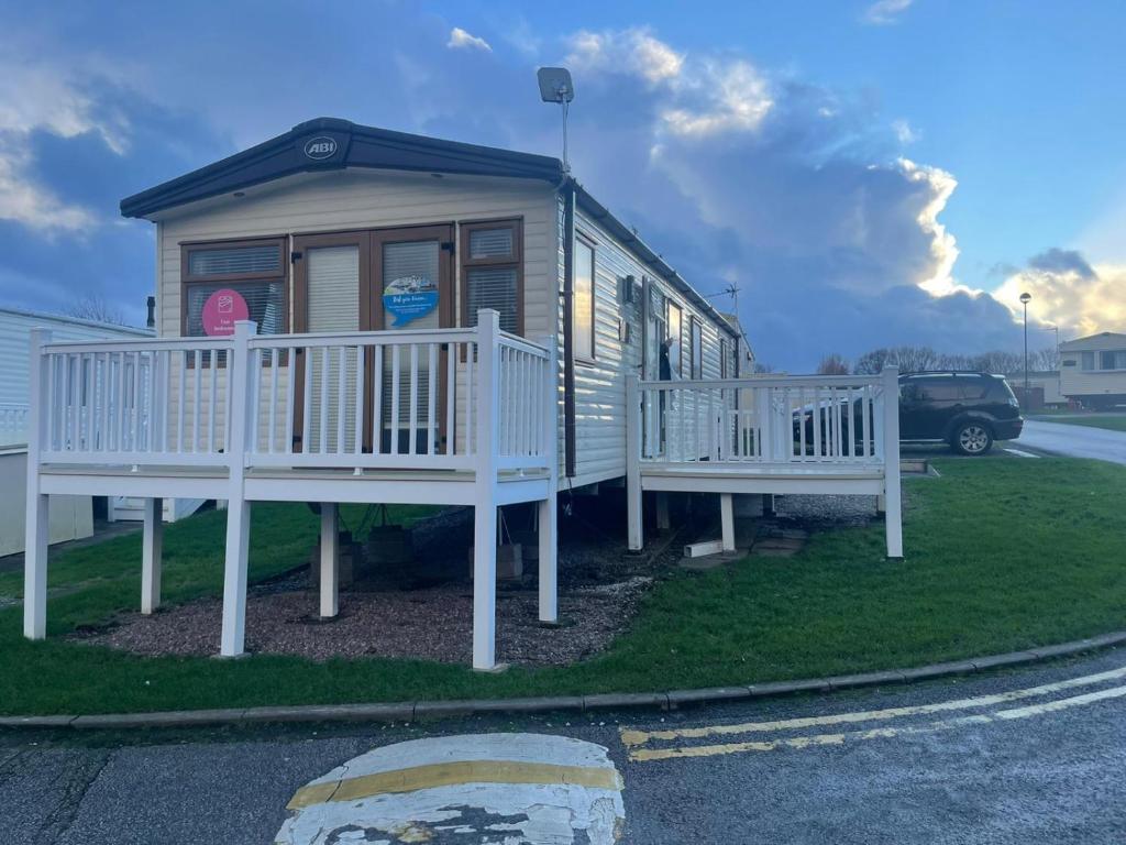 a small house with a porch and two benches at Luxury 6 Berth Caravan, Marton Mere in Blackpool