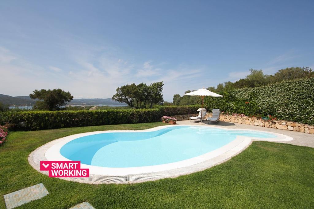 a swimming pool in the grass with an umbrella at Sa Pedra House by Wonderful Italy in Porto Rotondo