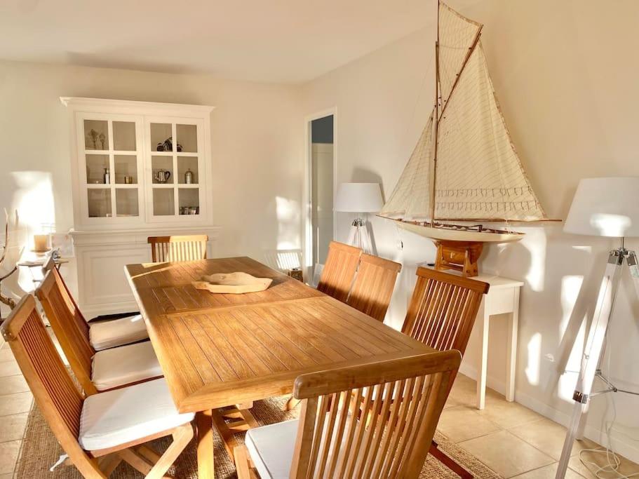 a dining room with a wooden table and a boat on the wall at Charmante Villa familiale à SAINTE CECILE PLAGE in Camiers
