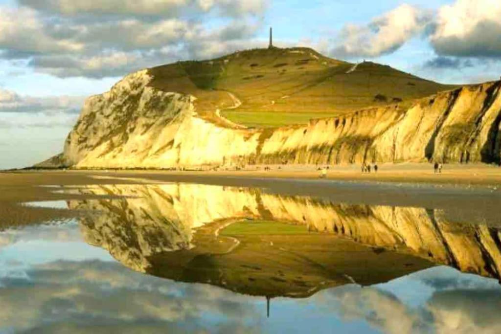 a reflection of a mountain in the water on a beach at Charmante Villa familiale à SAINTE CECILE PLAGE in Camiers