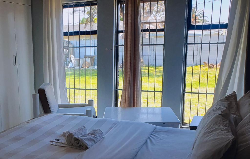 a bedroom with a bed and a table and large windows at Sweet Home39 Guest House Summerstrand in Port Elizabeth